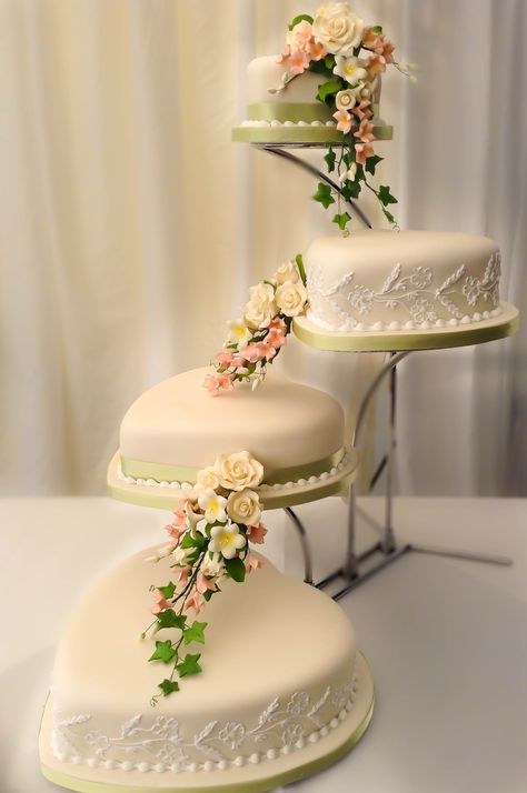 A stunning heart shaped wedding cake with lace piping on alternate tiers displayed on an offset stand.  The rose sprays cascaded down the tiers to enhance this beautiful classic look. Check out other ideas at https://regencycakes.com/classic-wedding-cakes-gallery #weddingcake #weddingcakedesign #classicweddingcake #heartweddingcake #modernweddingcake #weddingideas #weddingcakedecorator #weddinginspiration Wedding Cake Not Stacked, Heart Shaped Tiered Cake, Heart Shape Wedding Cakes, Wedding Cake Stand Ideas, Heart Cake Decoration, Heart Shaped Wedding Cakes, Heart Wedding Cake, Shaped Cakes, Heart Wedding Cakes