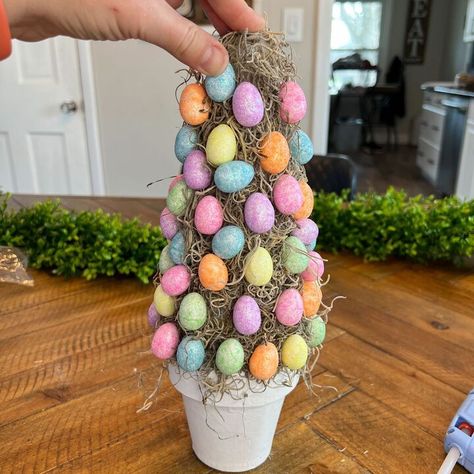 What a fun and festive way to decorate your home for Easter! This easy to make DIY topiary tree is Simple and Colorful for adding that POP of color to any room! Materials needed:3 packages of the Pastel Glitter Easter Eggs FolkArt Home Decor White Adirondack Chalk Paint 9" Styrofoam Cone 4" Paper Mache Flower Pot Natural Spanish MossGlue gunPaint brush Now that we have the materials - Let's get crafting! This first step we will take the chalk paint and cover the paper mache pot w… Easter Egg Tree Diy How To Make, Easter Egg Tree Diy, Easter Flower Pots, Glitter Easter Eggs, Diy Topiary, Dollar Tree Easter Crafts, Topiary Tree, Easter Egg Tree, Senior Center