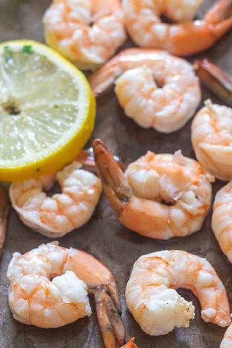 Juicy fresh shrimp that has been poached and sprinkled with lemon on a large tray.