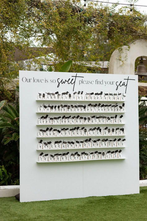 This San Diego wedding took place at Tivoli the Italian inspired wedding estate. A creative seating chart was designed, featuring a shelf adorned with cookies, each bearing the name of a guest. These yummy treats were more than just a place card; they also featured the couple’s personal monogram. Photographer: JC Jones | Seating Chart Wall: Rent Boho Babes Seating Chart Cookies, Creative Seating Cards Wedding, Wedding Seating Chart Favors, Coffee Wedding Seating Chart, Wedding Favor Seating Chart Ideas, Creative Seating Chart Wedding Party Favors, Custom Wedding Seating Chart, Custom Seating Chart Wedding, Cookie Seating Chart Wedding