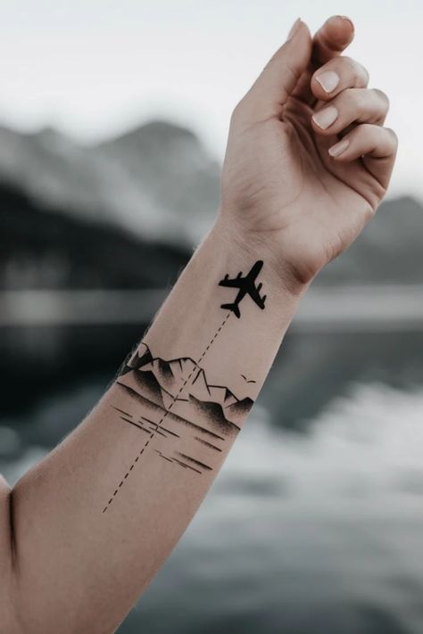 Airplane tattoo on arm with mountain silhouette and dotted flight path. Train Tattoo Small Simple, Airplane Tattoo Ideas, Traveling Tattoos, Aviation Tattoo, Tattoo Ideas For Females, Train Tattoo, Couple Tat, Airplane Tattoo, Plane Tattoo