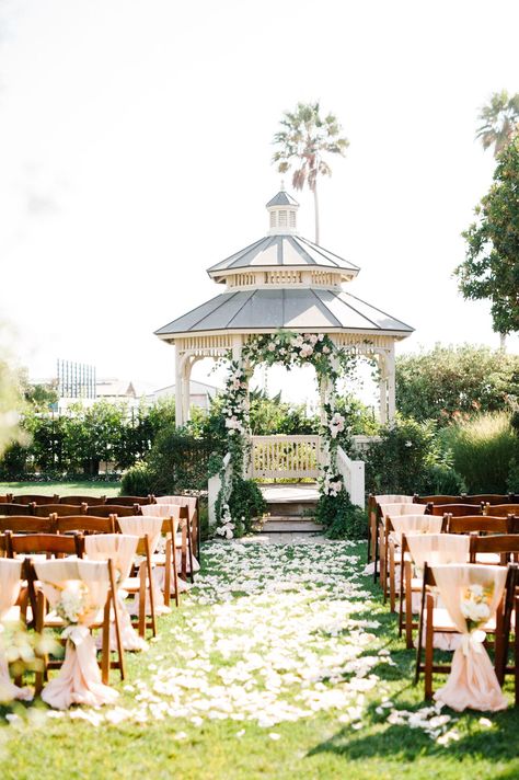 Ceremony Chair Decorations at timeless garden wedding ceremony on California's Central Coast. Ceremony gazebo drapped florals and isle peddles for beach sunset intimate Caycuos Wedding venue. Blush linen wrapped wooden chairs tied with ivory satin ribbon and white rose floral clusters hanging on back. Classic and elgant Cass House Wedding. Photographed by San Luis Obispo Wedding Photographer  Austyn Elizabeth Photography. Lawn Ceremony Decor, Garden Wedding Gazebo, Gazebo Garden Wedding, Rose Garden Wedding Ceremony, Wedding Venues Gazebo, Flowers On Gazebo Wedding, Ceremony Gazebo Decorations, Gazebo Ceremony Decor, Beach Gazebo Wedding