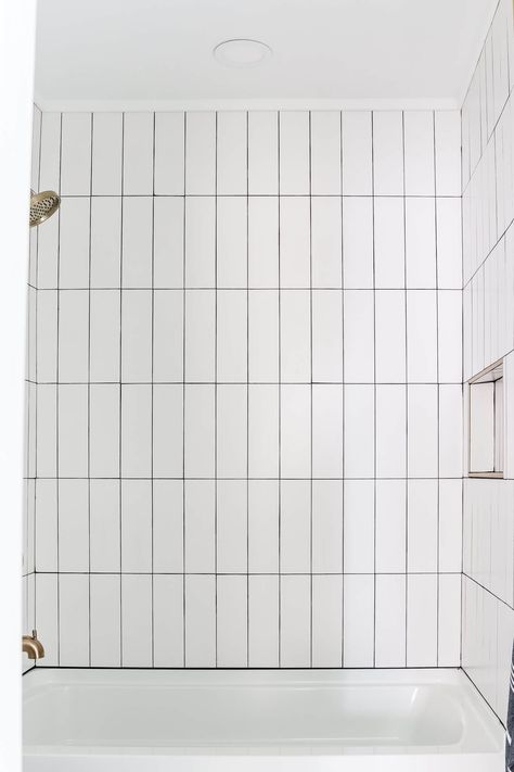 Vertical Tile Around Bathtub, Vertical Stack White Subway Tile, White Vertical Stacked Subway Tile Bathroom, Vertical Subway Tile Tub Surround, Subway Tile Hung Vertically, Vertical Shower Tile Wall, Shower Tile With Black Grout, Shower Tile Black Grout, White Vertical Stacked Subway Tile