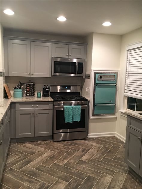 Gray cabinets, vintage wall oven, teal accents, herringbone tile flooring pattern Gray And Turquoise Kitchen, Gray And Aqua Kitchen, Teal Grey Kitchen, Teal Accents In Kitchen, Teal Kitchen Accents, Gray And Teal Kitchen Ideas, Teal Kitchen Decor Ideas, Teal And Gray Kitchen Decor Ideas, Grey And Aqua Kitchen