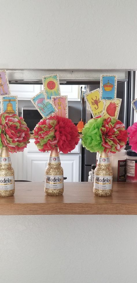 Beautiful Modelo glitter bottle with 3 tissue Mexican flowers and loteria cards. Taco Party Centerpiece Ideas, Centerpiece For Fiesta Party, Mexican Theme Party Decorations Centerpieces, Modelo Bottle Centerpieces, Mexican Themed Party Centerpieces, Three Esta Centerpieces, Mexican Theme Graduation Party Centerpieces, Mexican Theme Table Centerpieces, Fiesta Theme Table Centerpieces