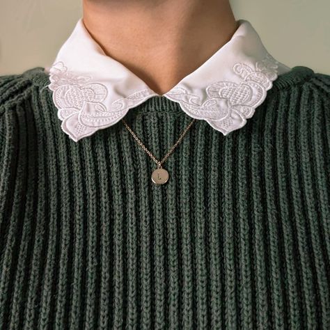 This photo shows the area of a body below the chin and just above the chest. It's zoomed in to show the texture on the dark green, cable-knit sweater worn over a cream-colored button down with swirly embroidery on the collar. Underneath the collar there is a dainty gold chain that hangs down with a gold circle stamped with the letter 'L'. This image is an emphasis on cozy textures. Collar Over Sweater, Collared Shirt Under Sweater Outfit, Sweater Collared Shirt Outfit, Collar Under Sweater Outfit, Collared Shirt With Sweater, Collard Shirt Under Sweater, Collared Shirt Under Sweater, Shirt Over Sweater, Collar Under Shirt