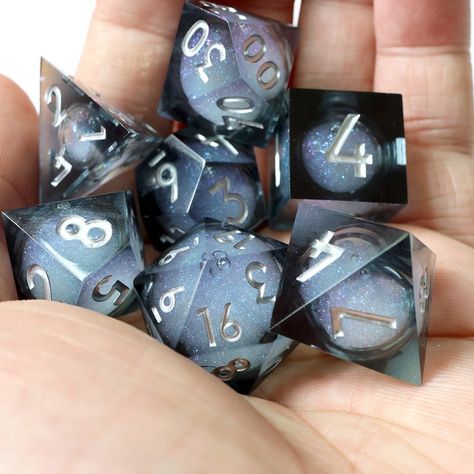 Rolling these dark liquid core dices is like unleashing a miniature disco party right on your tabletop! Each piece is a cocktail of translucent black resin and shimmering flakes, with a glitter-dusted liquid center that lights up like a rogue’s smile when it catches the light. Liquid Core Dice, Dnd Journal, Pretty Dice, Dice Goblin, Resin Dice, Glitter Dust, Dice Games, Black Resin, Skyfall