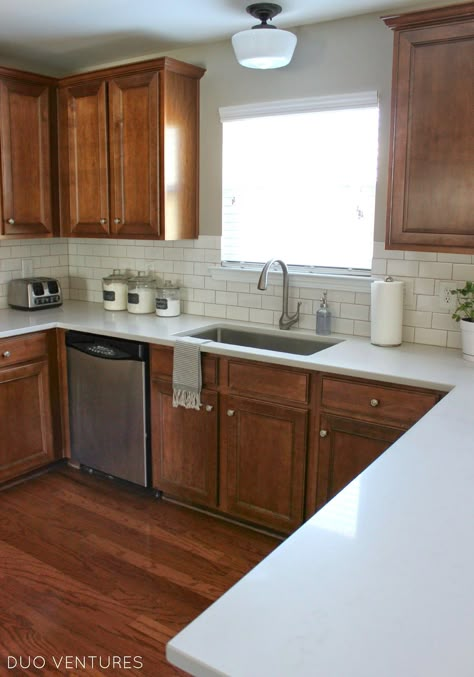 Brown Cabinets With White Backsplash, Brown Cubbards Kitchen, White Counter Brown Cabinets, White Counter Backsplash Ideas, Apartment Kitchen Brown Cabinets, Brown Kitchen With White Counter, White Backsplash Brown Cabinets, White Countertops Brown Cabinets, White Kitchen With Brown Cabinets