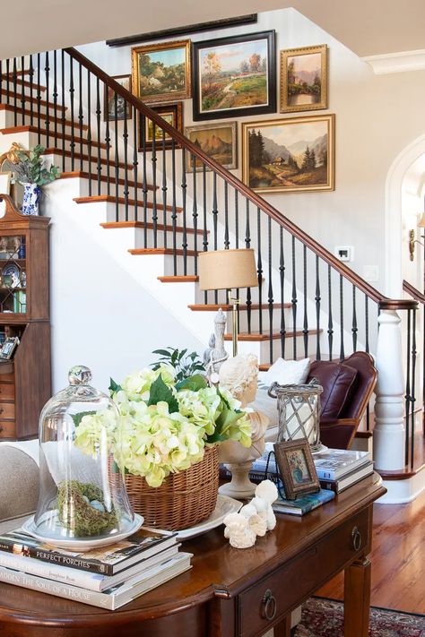 Create this cottage-style table vignette with baskets, a bust, spring flowers, books, and white china that can adapt to any type of table. #consoletable #springdecor #cottagestyle Traditional Sofa Table Decor, Vintage Lowcountry Decor, Two Chairs With Table In Between, Fresh Home Decor Ideas, Side Table Vignette, Grandmellinial Style, White Wall Interior Design, Spring Dining Room Table Decor, Traditional Cottage Decor