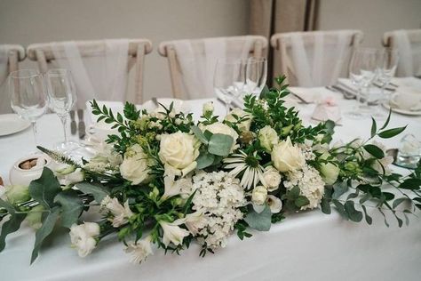 Classic green and cream flowers in Nathan and Chelsea's long and low table arrangement in the Doddington Hall coach house. The arrangement included roses, eucalyptus, alstromeria and lisianthus. 📷 Martin Cheung Photography White And Green Long And Low Flower Arrangement, Low Long Flower Arrangements, Long And Low Floral Centerpiece, Long And Low Flower Arrangement, Wedding Top Table Flowers, Green And Cream Wedding, Table Centre Pieces Wedding, Staircase Flowers, White Table Decorations