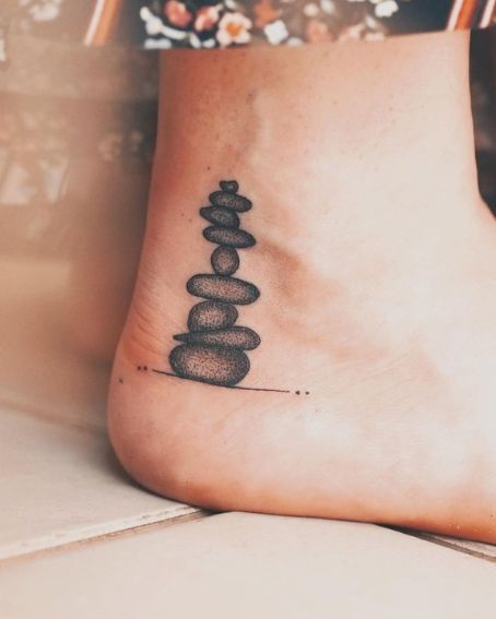 15 Beautiful Ankle Tattoos and Their Meanings You May Love to Try! Zen Tattoos For Women, Shin Ankle Tattoo, Mens Ankle Tattoos Ideas, Ebenezer Stone Tattoo, Tat Cover Up Ideas, Rock Tattoo Ideas Stones, Petoskey Stone Tattoo, Cover Up Tattoo Ankle, Rocks Tattoo Stone