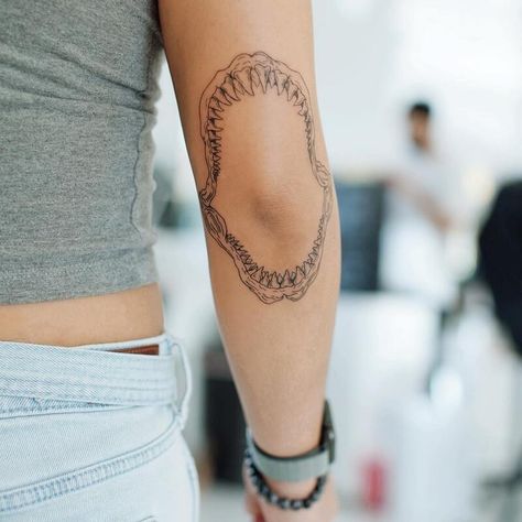 23 Shark Tattoo Ideas and Meanings - 2023 Guide Sharks Mouth Tattoo, Shark Jaw On Elbow Tattoo, Lil Shark Tattoo, Shark Sleeve Tattoo Women, Shark Mouth Elbow Tattoo, Shark Jaw On Elbow, Shark Tattoo Elbow, Aquatic Sleeve Tattoos For Women, Shark Jaws Tattoo Elbow