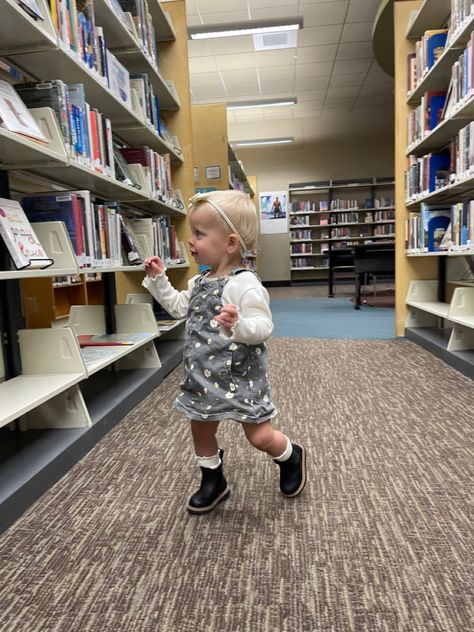 Toddler girl walking in a library wearing a fall outfit: black chelsea boots, a white bow, white knee-high socks, a cream shirt and black jean overall dress. Toddler Ruffle Socks Outfit, Toddler Boots Girl Outfits, Girls Boots Outfit, Black Chelsea Boots Outfit, Girls Chelsea Boots, Fall Toddler Outfits, Toddler Fall Outfits Girl, High Socks Outfits