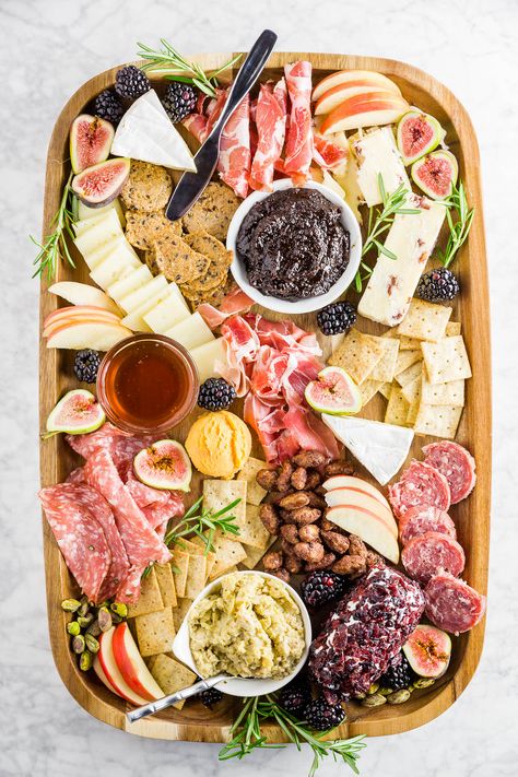 A wooden cheese board filled with cured meats, cheeses, apples, fig jam, berries and crackers. Harvest Charcuterie Board, Thanksgiving Charcuterie Board, Thanksgiving Charcuterie, Charcuterie Platter, Charcuterie Cheese, Snack Board, Charcuterie And Cheese Board, Charcuterie Recipes, Fig Jam