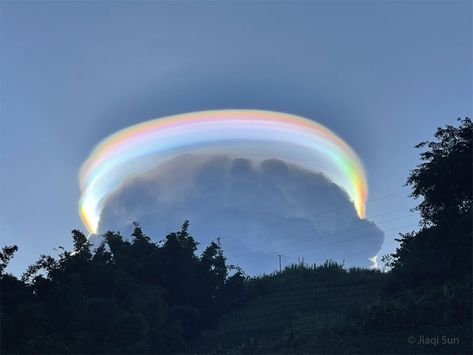 An Iridescent Pileus Cloud over China Yes, but how many dark clouds have a multicolored lining? Pictured, behind this darker cloud, is a pileus iridescent cloud, a group of water droplets that have a uniformly similar size and so together diffract different colors of sunlight by different amounts. The featured image was taken last month in Pu'er, Yunnan Province, China. Also captured were unusual cloud ripples above the pileus cloud. The formation of a rare pileus cloud capping a common cumulus Pileus Cloud, Water Droplets, A Group, The Sky, Trees, China, Sun, Water