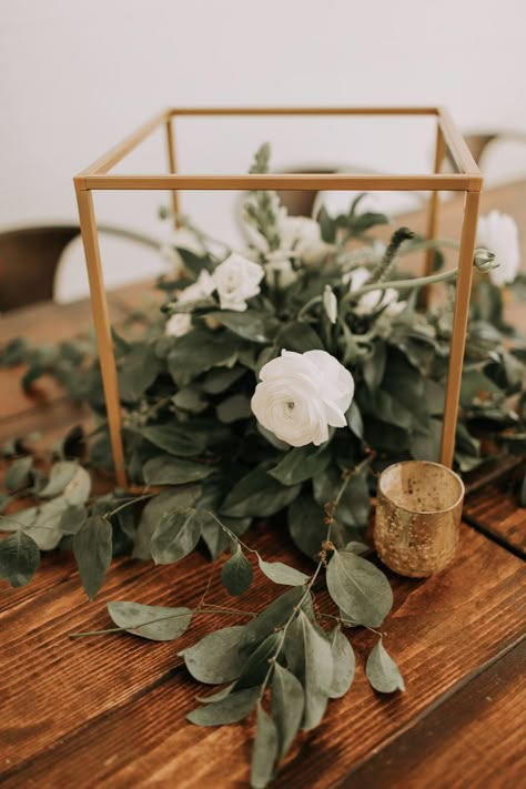 These farmhouse tables are gorgeous with a trail of green garlands with white florals. Add taper candles and gold accents to complete this classic wedding vibe. Green White Gold Wedding Decor Simple, Gold And Eucalyptus Centerpiece, Gold And Greenery Wedding Centerpieces, Sage Green Gold White Wedding, Sage Green And Cream Wedding Decorations, White Tan Green Wedding, Gold And Green Wedding Centerpieces, Moss Green And Gold Wedding, White Green Gold Wedding Centerpieces