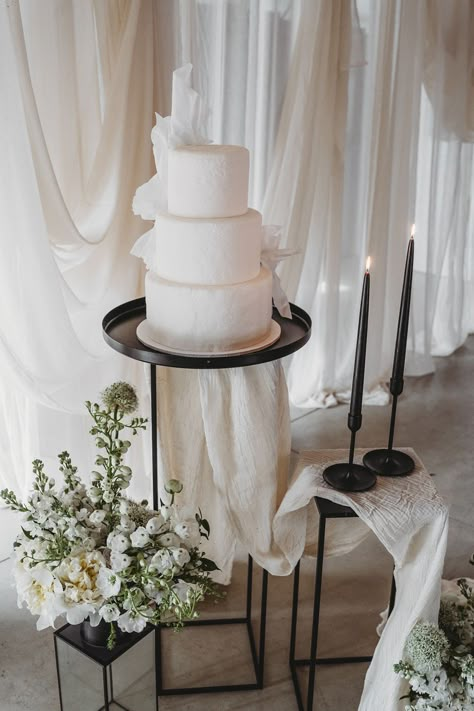 Three tier white iced vegan wedding cake with black taper candles and wedding drapes Wedding Cake Black And White, Wedding Cake Setup, Wedding Cake Black, Cake Black And White, Drapes Wedding, Wedding Cake Display Table, Wedding Drapes, Wedding Cake Table Decorations, Wedding Cake Setting