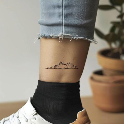 Capture the essence of wanderlust with this minimalist mountain range tattoo, inked just above the ankle—a symbol of adventure and the journey ahead. Save this for your next ink inspiration and follow for more! ✨ Framed by the frayed edges of rolled-up blue jeans, this simple line drawing adds a touch of the great outdoors to every step. Perfect for those who carry the spirit of exploration in their souls. #MountainTattoo #MinimalistInk #Wanderlust #AdventureA Minimalist Mountain Tattoo, Mountain Range Tattoo, Mountain Tattoo Design, Simple Line Drawing, Minimalist Mountain, Ink Inspiration, Simple Line Drawings, Mountain Tattoo, Minimal Tattoo