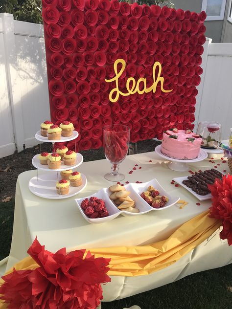 Belle birthday theme party . Yellow and red decorations . Simple dessert table set up . Backdrop are paper red roses with child’s name in the middle . Red Yellow Birthday Theme, Yellow And Red Party Decor, Red And Yellow Decorations Party, Rose Birthday Party Theme, Red And Yellow Graduation Party Ideas, Red Roses Themed Birthday Party, Red Roses Party Theme, Red Rose Party Theme, Red Roses Birthday Party Ideas