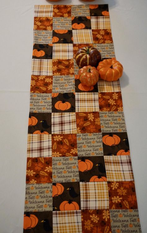 Welcome Fall Table Runner - this patchwork runner features squares that say Welcome Fall, plaid squares, autumn leaves, and this cute little crow guarding his pumpkin!  Patchwork front, and a plain cream cotton for the backing. This table runner is approximately 12 inches wide by 48 inches long.   Table runners dress up your kitchen or dining room tables, but also look great on sofa tables, mantels, sideboards, dressers, etc.  This pattern will add just the right whimsical touch to your autumn decor.  Suitable for everyday use or holidays.   It will lay flat and not bunch up.  Machine washable in cold on gentle cycle. Please note that colors may vary in appearance depending on the device you're using.   I'm happy to make one to your custom length and width, however this fabric is not neces Fall Quilt Table Runners, Quilted Pumpkin Table Runner, Autumn Quilted Table Runner Patterns, Fall Table Runners Patterns Free Easy, Quilted Fall Table Runners, Patterns For Table Runners, Pumpkin Table Runner Free Pattern, Fall Table Runners Patterns Free, Sewing Table Runners