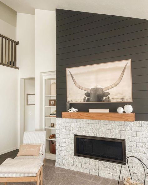 A bold charcoal gray shiplap wall above the stone fireplace accentuates this living space's bright neutrals. A wood-framed bull portrait hangs along the wall over the natural wood mantle with ceramic vases. Charcoal Shiplap Wall, Natural Wood Mantle, Gray Shiplap Wall, Shiplap Accent Walls, Evolve Stone, Bull Portrait, Diy Shiplap Fireplace, Gray Shiplap, Farmhouse Shiplap