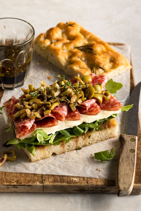 Salami, brie and rocket sandwich, served on rosemary salted focaccia bread with chopped green olives, fresh thyme and a balsamic glaze. The ultimate sandwich shot. Photographed by London food photographer Samantha Couzens. Head to my portfolio to get more inspiration for your next sandwich shoot. #Hot&ToastySandwichDelights Focaccia Sandwich Photography, Naan Bread Sandwich, Sandwiches Photography Styling, Sandwich Photography Ideas, Naan Bread Sandwich Ideas, Recipes With Salami, Focaccia Ideas, Focaccia Sandwich Ideas, Rocket Sandwich