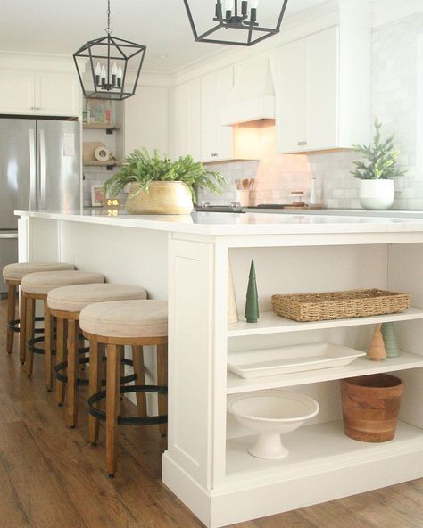 I always need more storage space in my home, so I may have to copy this designer and add some built-in shelves to the end of my kitchen island. The added space is perfect for displaying those items that are seldom needed but nice to keep on hand. I'm also captivated by the use of pine boughs as decorations on the island and kitchen counter, adding an organic touch to the white cabinets and counters. Shelves On Kitchen Island, End Of Kitchen Counter Ideas, Island With Shelf On End, Island With Shelves On End, Kitchen Island End Storage, Kitchen Island Shelves On End, Kitchen Island Shelves Decor, Kitchen Island Side Panel Storage, Sink Not Centered On Island