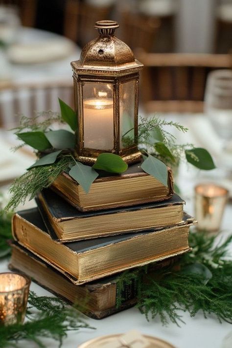 Elevate your wedding or special event with charming book centerpieces! Explore decor ideas that incorporate vintage books, flowers, and candles to create a whimsical and elegant atmosphere. Ideal for graduations, baby showers, and more, these centerpieces will captivate your guests and add a personal touch to your celebration. Book And Candle Wedding Centerpieces, Book Lantern Centerpieces, Lantern Flowers Wedding, Diy Book Centerpieces, Farewell Party Centerpieces, Books For Centerpieces, Vintage Lantern Wedding Decor, Book Party Centerpieces, Book Table Centerpieces