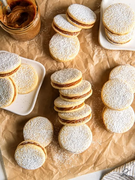 dulce de leche sandwich cookies (alfajores) dusted with powdered sugar on parchment paper. Christmas Alfajores, Alfajores Recipe Argentina, Easy Alfajores Recipe, Alfajores Recipe, Piped Cookies, Powdered Sugar Cookies, Healing Your Gut, Buttery Shortbread Cookies, Frozen Cookies