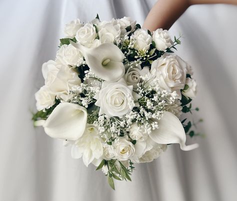 These beautiful artificial wedding bouquets are made from faux flowers of white and off white, sage greenery and silk eucalyptus. They will make the perfect addition to your big day!  This bridal bouquet consists of white roses, calla lilies and dahlia with green silk eucalyptus and sage greenery and fillers. The stems are wrapped in twine. The bridal bouquet pictured is 12" (30 cm). Bouquet Size Available: Bridal Bouquet- 12" (30 cm) Bridesmaids Bouquet - 7" (17 cm) Toss bouquet 6" (15 cm) Matc Wedding Tossing Bouquet, Different White Flowers Bouquet, All White Roses Bouquet, Fresh Bouquet Flowers Wedding, Wedding White Flowers Bouquet, White And Beige Bridal Bouquet, Flower Arrangements White Roses, White Boquetes Of Flowers Wedding, White And Green Bridesmaid Bouquet