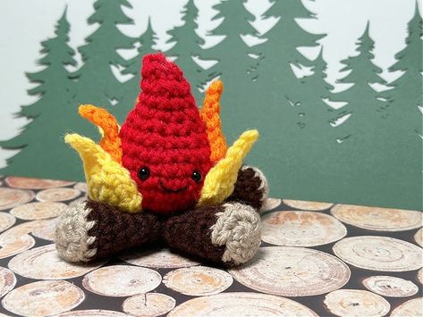 The pattern for day 10 of the camping themed summer mini amigurumi crochet along is a cozy little campfire. Red orange and yellow flames on logs. Crochet Flames Pattern, Crochet Camping Ideas, Crochet Flame, Crochet Dumpster Fire Pattern Free, Camping Crochet Patterns, Crochet Bonfire Blanket, Crochet Campfire, Campfire Blanket Crochet Pattern, Crochet Woodland