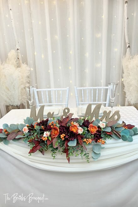 Sweetheart Table Arrangement for Wedding Centerpiece | TheBridesBouquet.com Wedding Center Piece Ideas Fall, Fall Wedding Floral Table Arrangements, Flowers For Bride And Groom Table, Fall Wedding Sweetheart Table Decor, Sweetheart Table Wedding Rustic Fall, Wedding Head Table Flowers Arrangements, Flower Wall Head Table Wedding, Fall Bride And Groom Table, Fall Wedding Sweetheart Table Flowers