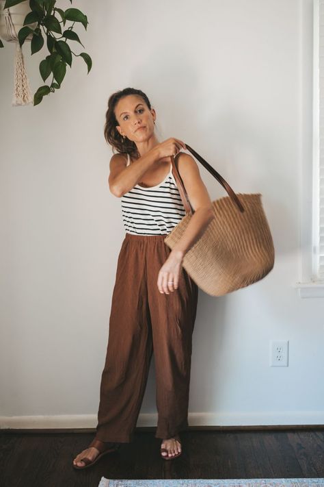 ashley wearing a white and navy striped top, brown drapey pants, brown leather sandals, a tan woven tote bag, and tan frame sunglasses Cool Mum Outfit Summer, Mum Fashion 2024 Summer, Boho Mom Outfits, Striped Tank Top Outfit, Brown Sandals Outfit, Goal Outfits, Brown Linen Pants, 2024 Clothes, Minimalist Fashion Summer