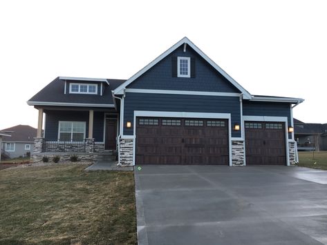 blue siding, blue shakes, carriage style garage door, light stone Brown Garage Doors Blue House, Dark Blue House Exterior With Stone, Blue Siding With Stone Exterior, Blue House Brown Garage Door, Blue House With Brown Garage Door, Navy Blue House Exterior With Stone, Garage Door Colors With Blue House, Blue House Garage Door Color, Slate Blue Siding Exterior