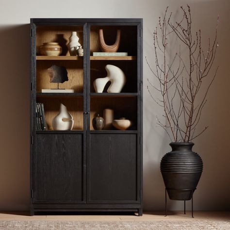 Matte black drifted oak frames lighter interior shelving for subtle but striking contrast. Glass doors allow for prized possessions to dazzle on full display while spacious cabinets add out-of-view storage. Glass Door Cabinet, Frame Light, Glass Cabinet Doors, Door Cabinet, Black Cabinets, Kiln Dried Wood, Glass Cabinet, Pottery Barn Teen, Four Hands