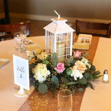 White candle lantern surrounded by flowers for a wedding. Lantern With Candle, Flowers For A Wedding, Types Of Eucalyptus, Lantern Wedding, Lantern Centerpiece Wedding, Pink And White Roses, Surrounded By Flowers, Roses White, White Hydrangea