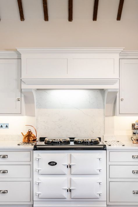 Head on shot of the beautiful AGA in the middle of the kitchen units. A bepsoke extractor hood sits above for perfect extraction from the AGA, and a stunning design to go with the exposed beams in this hub of the home.   #classicshaker #matchingtye #handmade #handpainted #shaker #handmadekitchens #handbuilt #shakerfurniture #armacmartin #quartzworktop #noblecarrara #aga Kitchen Mantle Over Aga, White Aga Kitchen, Canopy Hood Kitchen, Shaker Kitchen Hood, Aga Mantle, Handmade Kitchen, Built In Extractor Hood, Built In Cooker Hood, Built In Hood