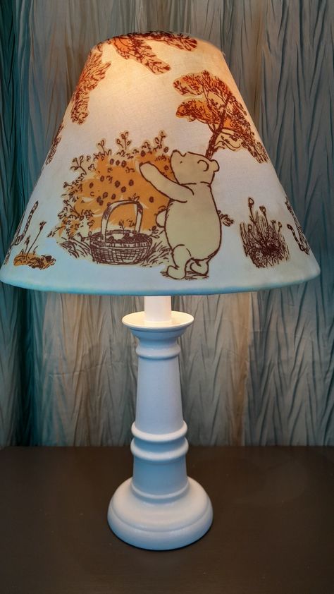 This sweet Winnie the Pooh Nursery accent lamp features first a hand dyed cotton cream/yellow and white fabric, covered with fabric appliques of Pooh, Tigger, Eeyore, Piglet, and Christopher Robin. The shade fits on any lamp base, sitting on the socket above the light bulb on a suspended ring. The shade itself measures 7 1/4 in High by 10 in wide and fits a base up to 12 in in height. The shade can be purchased alone, or with the lamp base. The assembled lamp offered is 15 and a half inches tall. The hand painted and sealed base comes in your choice of white or cream. Base color options can be viewed in the photo gallery. What a perfect gift this would make for any baby's Winnie the Pooh nursery. Winnie The Pooh Nursery Ideas, Winnie The Pooh Baby Nursery, Vintage Winnie The Pooh Nursery, Pooh Bear Nursery, Nursery Winnie The Pooh, Winnie The Pooh Nursery Decor, Base Sitting, Baby Lamp, Winnie The Pooh Decor