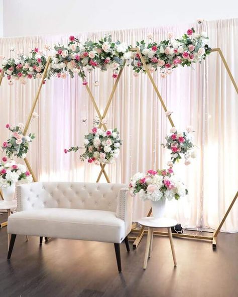 Create a lovely stage backdrop to elevate your event design up by several notches. Ooze festive radiance by draping white chiffon curtains on a backdrop stand and set up multiple gold hexagonal wedding arches in front to create a gorgeous geometric visual appeal. Bring a touch of class and liveliness by decorating the arches with eucalyptus garlands and further beautify them with beautiful blush roses and ivory silk flowers. Hexagon Arch Decor, Event Space Decor, Arch Wedding Decor, Hexagon Arch, Event Decor Ideas, Party Decorations Table, Wedding Card Design Indian, Hexagon Wedding, Arch Decor