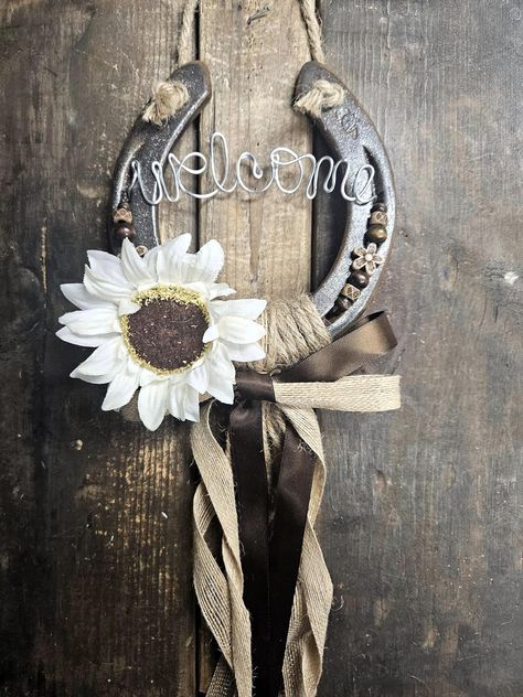 Add a little luck and prosperity to your home or barn with this rustic hanging horseshoe  The perfect gift for- Housewarming present -New barn -Birthday -Gift for a horselover -Made with upcycled horseshoes -Painted with a clear glitter finish -Adorned with Mahogony &  Cream beading - White Sunflower  -Rustic accents with jute & burlap ribbon -Twisted wire Welcome sign -Perfect to hang in your favorite room or use as a stall sign  **Allow 3-5 business days to process **Allow 1-3 business days af Horse Shoe Gift Ideas, Horse Shoe Decor Ideas, Diy Horse Shoe Decor, Horseshoe Windchimes, Horse Shoes Crafts, Western Home Decor Diy, Western Crafts Diy, Upcycled Horseshoes, Painted Horseshoes