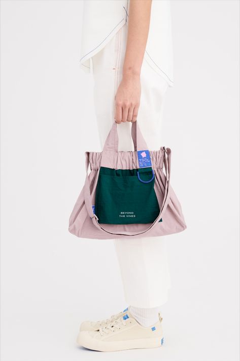 A product line designed at the studio of Beyond The Vines for Pokémon. This water resistant nylon bag is designed with short handles and an adjustable crossbody strap. It features a large colourblock front flap pocket, a contrast D-ring to attach your keys to and an elasticated opening with a hidden magnetic closure. Featuring a Jigglypuff label on the strap for this special edition, the Dumpling Bag is also lightweight and packable. Beyond The Vines Dumpling Bag, Beyond The Vines, Pokemon Shop, Colourful Aesthetic, Pokemon Jigglypuff, Pokemon Mew, Reversible Bag, Dumpling Bag, Woven Labels