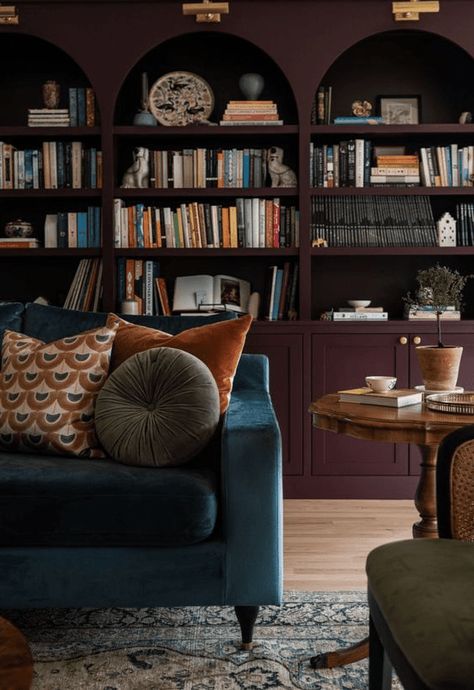 a refined and moody space with aubergine arched bookcases, a navy sofa with pillows, a vintage table and a green chair Arched Bookcases, Burgundy Living Room, Home With Color, Moody Living Room, Seattle Homes, Library Room, House Vibes, Banquette Seating, Renovation Design