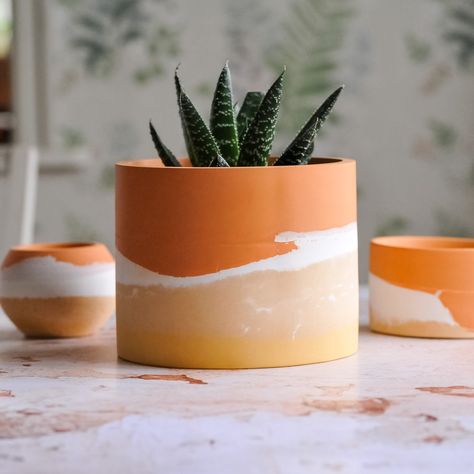 Here you have/get 3 planters to add a boho feeling into your room.  We love colors, so here you have 3 plant pots made with layers of (orange, white and ocra yellow earth pigments). These planters are perfect to be used indoors as apart of your home decor or in the green house to add a pop of color. CARE INSTRUCTIONS: *Avoid contact with oily or coloured liquids as they may stain the surface. *Clean by gently wiping with a damp cloth. *Don't scrub.  *Don't dishwash. This order is for a 3 plant p Colourful Plant Pots, Ceramic Pot Painting Ideas, Colorful Plant Pots, Paint Vase, Painted Plant Pot, Garden Center Displays, White Flower Pot, Buddha Candle, Plant Pot Design