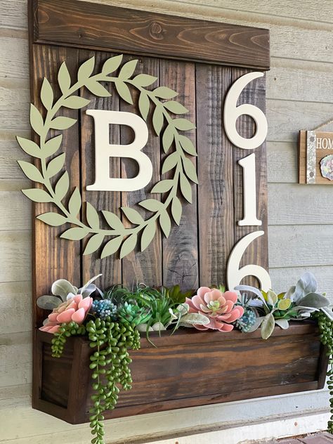 "Our beautifully handmade address planter boxes are sure to bring warmth and charm to any home or office. These handmade address plaques are a unique way to display your address while adding charm with the planter box attached. Our planters are sure to brighten any entrance of your home or office.  Our address planter boxes are made from carefully selected wood. You choose your choice of stain or just leave it natural. Add up to 5 numbers to your planter box. Each planter box is sealed to be protected against the weather and its elements. Our planter boxes are designed for either real or artificial plants or flowers. Flowers are not included unless otherwise custom ordered. The address plaque can also be personalized with last name initial inside a leaf reef just custom order and we will s Planter Box Porch, Planter Boxes In Front Of House, Small Back Porch Decorating Ideas, Address Planter Box Diy, Planter House Number, Diy Address Sign With Planter, Planter Box Address Sign Diy, Wooden Address Front Yard Signs With Flower, Wood Address Sign With Planter