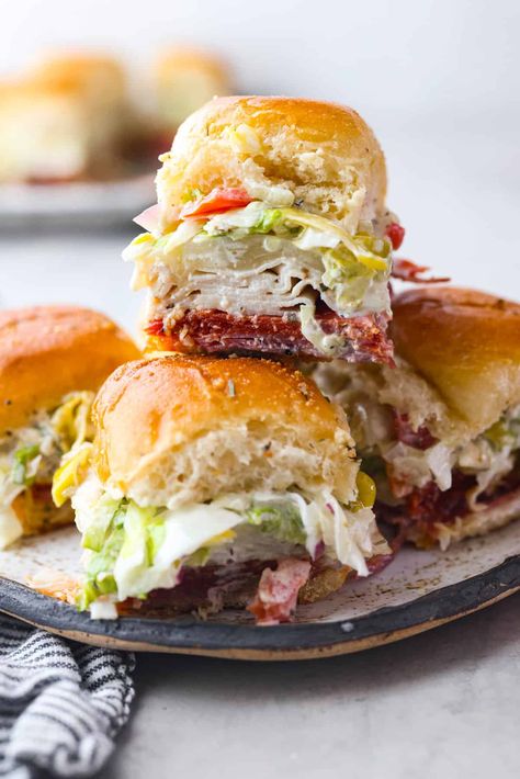 The classic grinder sandwich made into sliders to share! You've got Hawaiian rolls topped with layers of pepperoni, salami, turkey, provolone, and creamy grinder salad. And to top things off- each roll is brushed with a buttery parmesan glaze and baked to golden brown perfection. Italian Grinder Sliders, Grinder Sliders, Healthy Sliders, Tailgate Foods, Hawaiian Roll Sandwiches, Grinder Salad, Sliders Recipes Hawaiian Rolls, Grinder Sandwich, Pepperoni Recipes