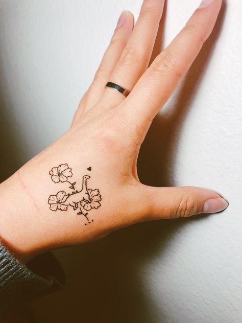 Dainty dinosaur tattoo with hibiscus flowers! Womens Dinosaur Tattoo, Dinosaur Friend Tattoo, Dinosaur Tattoo For Daughter, Dino Flower Tattoo, Pretty Dinosaur Tattoo, Matching Dinosaur Tattoo Best Friends, Dino With Cowboy Hat Tattoo, Dinosaur Holding Knife Tattoo, Cute Dinosaur Tattoos For Women