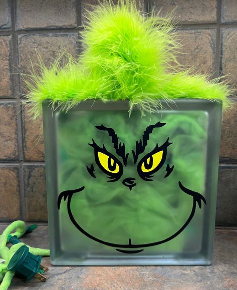 "Unique piece to decorate the holidays with! Grinch frosted glass block 7 3/4\" by 7 3/4\" with green 50 count LED Christmas lights, green tulle, vinyl face and fur Snowman  Glass block 7 3/4\" by 7 3/4\" with 120ct cool white LED plug-in fairy lights, white tulle and vinyl face Deer Farmhouse   Glass block 7 3/4\" by 7 3/4\" with 120ct multicolored LED plug-in fairy light, vinyl design, red tulle and buffalo check ribbon bow. Gnome Christmas Glass block 7 3/4\" by 7 3/4\" with 120ct multicolored LED plug-in fairy light, vinyl design, red tulle and buffalo check ribbon bow. Each piece is handcrafted by me. Due to this there may be a slight variation in your finished product and the one pictured." Glass Blocks Christmas Ideas, Fairy Lights White, Christmas Crafts Ideas, Christmas Glass Blocks, Decorative Glass Blocks, Raffle Ideas, Glass Block Crafts, Painted Snowman, Christmas Blocks