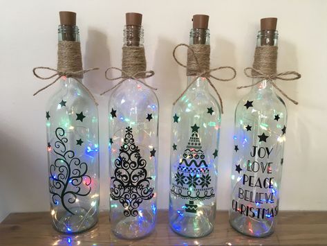 Light up wine bottles with Christmas themes Painted Light Up Bottles, Wine Bottle Crafts Christmas Lights, Christmas Wine Bottle Lights, Wine Bottle Cricut Projects, Cricut Glass Bottle Ideas, Light Up Wine Bottles Christmas, Painted Wine Bottles Christmas Ideas, Christmas Wine Bottles Cricut, Cricut Christmas Wine Bottle Ideas