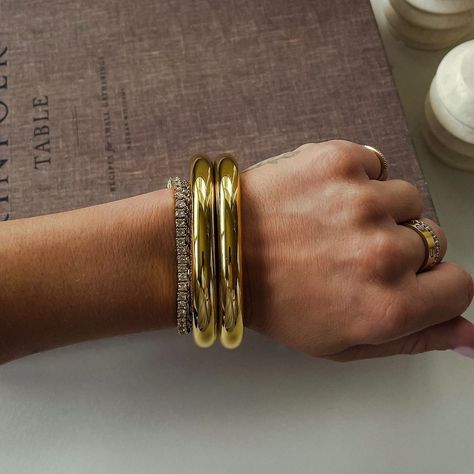 Noor Bangles back in stock 🤍🎀 These 18k gold irregular bracelets are stunning with a high-gloss shine and a natural flowing shape. We highly recommend stacking and layering these bangles to give a much more elevated look! You can also layer them with the tennis bracelet as seen in the second frame 🙂‍↔️ Price: N12,000 only. Please note that bangles are sold individually and not in stacks Chunky Bangle Bracelets, Gold Thick Bracelet, Gold Bracelet Bangle, Chunky Gold Jewelry, Stacking Bangles, Gold Bracelets Stacked, Open Bangle Bracelet, Gold Bangles For Women, Stackable Bangles