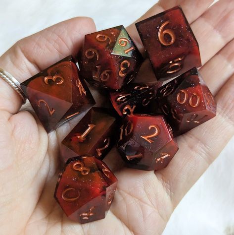 Introducing the "Blood and Smoke" Dice Set, a sharp edge 7-piece polyhedral dice set featuring haunting pools of blood cast in smoky resin, finished with an elegant copper font. Perfect for Dungeons and Dragons and many other exciting tabletop role-playing games, this acrylic set includes one of each: D20, D12, D10, D%, D8, D6, and D4. This Fennek & Finch exclusive is designed by Therin and comes in a cardboard jewelry box with cotton padding for safekeeping. Bring a touch of dark enchantment to Dice Sets Dnd, D&d Props, Dnd Dice Aesthetic, Clancy Aesthetic, Dice Ideas, Cool Dnd Dice, Dice Dragon, Dice Collection, Dnd Accessories